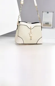 Detail of cream white bucket bag featuring pleated texture and rabbit pendant with crystal