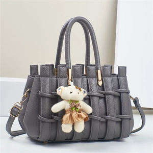 Detail of grey woven leather handbag with gold hardware and cute plush bear charm
