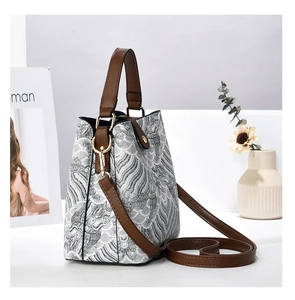 Dettaglio ricamo a onde su borsa a secchiello in pelle PU con fibbie d'oro e tracolla marrone