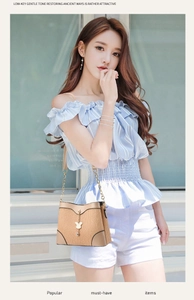 Close-up of beige bucket bag featuring vertical texture and golden bunny charm detail