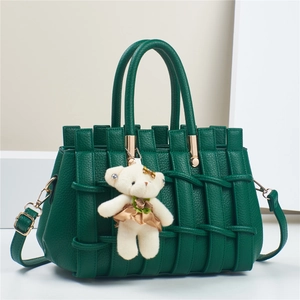 Detail of dark green woven leather handbag with gold hardware and white bear charm