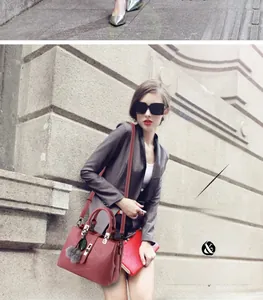 Detail of rose pink lychee leather handbag with decorative fur ball and green leaf charm