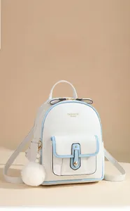 Close-up of white soft leather backpack with light blue edges and plush ball charm detail