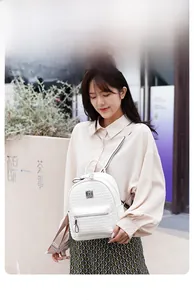 Détail d'un sac à dos blanc tressé avec zips argentés et bretelles en tissu réglables