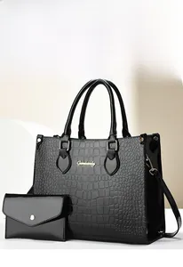 Detail of black crocodile embossed tote bag with matching envelope pouch and gold hardware