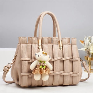 Close-up of beige lychee leather handbag with woven texture and gold hardware detail
