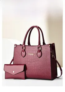 Detail of dark red crocodile embossed tote bag and matching clutch with golden hardware