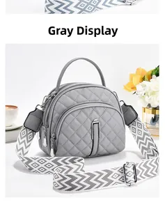 Détail du sac matelassé gris avec bandoulière géométrique large et fermetures éclair argent