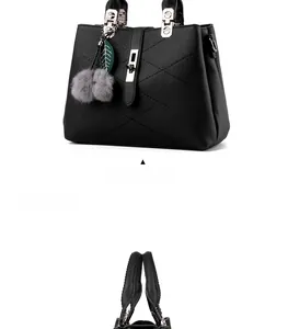 Macro shot of black pebbled leather handbag with silver buckles and plush pompom charm