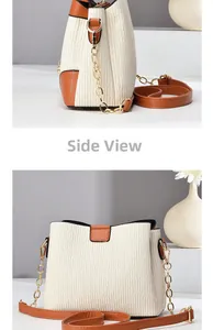 Detail view of cream bucket bag with vertical texture, side view, and gold chain strap