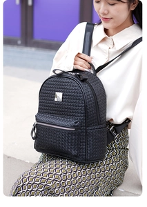Détail du sac à dos en cuir souple noir avec texture tressée et logo métallique chic