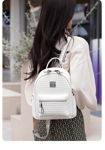 Détail d'un sac à dos blanc tressé avec plaque métallique sur un mannequin en extérieur