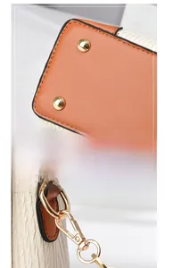 Detail of gold metal studs on brown leather base and textured beige fabric with spring clasp
