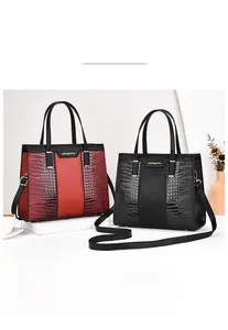 Detail of red and black tote bag featuring crocodile pattern leather and metal hardware