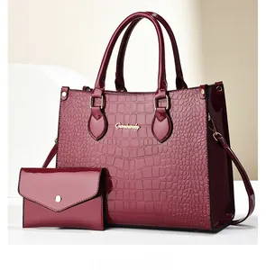 Detail of wine red crocodile pattern tote set with glossy finish and gold metal handles