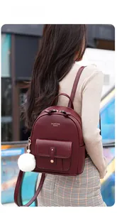 Deep red soft leather backpack with FASHION Queen logo and white pom-pom charm on model