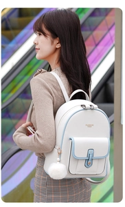 Close-up of white leather backpack with blue trim and a decorative white fur ball accessory