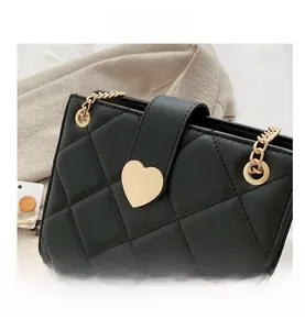 Detail view of black quilted leather bag featuring a gold heart-shaped metal buckle