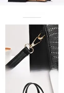 Detailed macro view of the gold-plated metallic hardware on a black crocodile pattern handbag