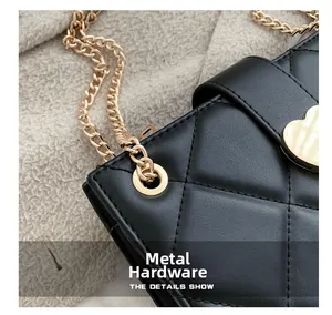 Detail of hardware perforation on black quilted leather bag with golden chain accent