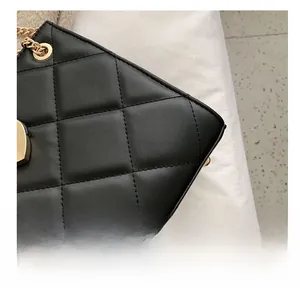 Close-up of black quilted shoulder bag with gold chain and heart-shaped metal lock