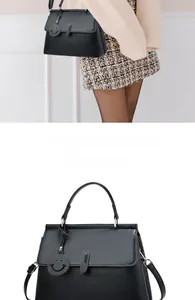 Details der schwarzen Handtasche aus Narbenleder mit Smiley-Anhänger und Schultergurt