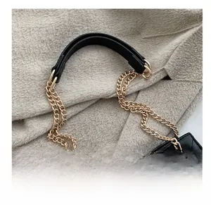 Detail of premium gold metal chain strap and quilted black leather on a chic tote bag