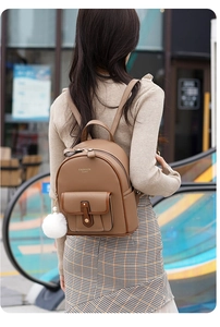 Brown faux leather backpack with diamond quilted pattern and white plush keychain on street