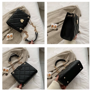 Detail of black quilted shoulder bag with gold heart clasp and protective bottom studs