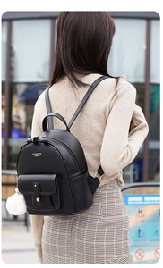 Close-up of black quilted PU leather mini backpack with a white faux fur pompom charm