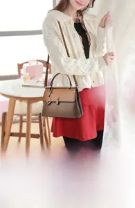 Detailsicht der braunen Lederhandtasche mit Metallgriff und Kontrastnähten für Damen