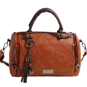 Brown vintage Boston bag in soft pebble leather with dual handles and cat tassel charm