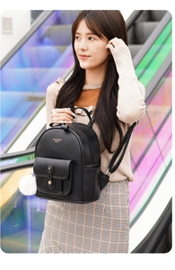 Close-up of black geometric quilted backpack featuring a white pompom and gold hardware