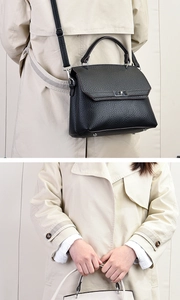 Detail der schwarzen Handtasche aus genarbtem Leder mit silbernen Beschlägen und Bodenfüßen
