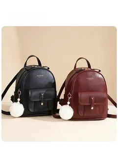 Detail of small textured faux leather backpacks with pearl and fur pompom charms