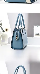Detail view of blue leather handbag with trapezoidal structure and golden zipper closure