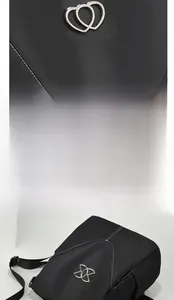 Détails d'un sac à dos noir en similicuir avec coutures blanches et logo cœur argenté
