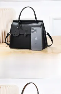 Detail der schwarzen Lederhandtasche mit Smiley-Anhänger und praktischem Schultergurt