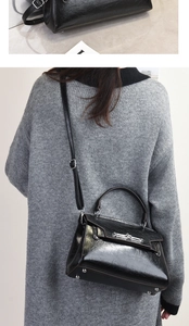 Detail of black oil-wax leather handbag with silver metal lock and adjustable strap
