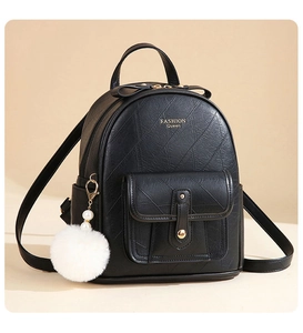 Detail of black faux leather backpack with embossed texture and pearl fur ball charm