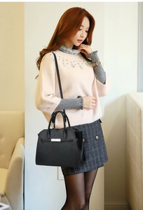 Detail view of black lychee grain leather handbag with silver lock shown on a model