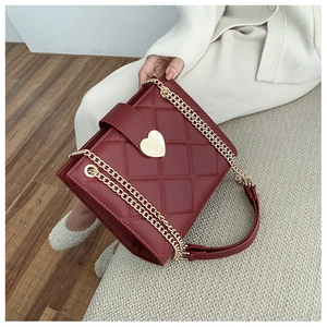 Detailed shot of dark red quilted tote bag featuring a golden heart shaped metal buckle