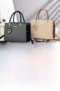 Detail of elegant handbags in black and beige with gold logo and pearl heart charm
