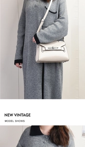 Detail view of a cream shoulder bag featuring vintage metal clasp and leather strap design
