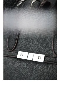 Detailed close-up of silver metal hardware and black lychee grain leather on handbag
