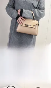 Detail of apricot glossy leather handbag with vintage metal buckle and top handle