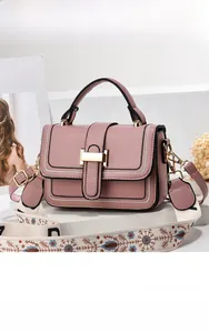 Nahaufnahme der rosa Lederhandtasche mit goldener Schnalle und besticktem breitem Gurt