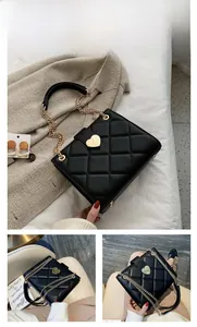 Detail of black quilted leather handbag featuring a golden heart-shaped twist lock buckle
