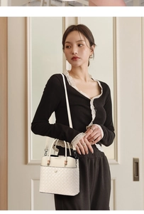 Detail of cream-white woven leather tote bag showing fine texture and sleek handles