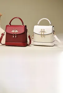 Détail de sacs à main en cuir rouge et blanc avec boucles cygne dorées et perles